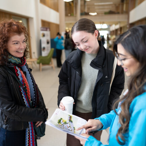 Student ambassador showing campus map at open day to two visitors